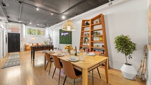 A dining area with a wooden table, chairs, and a hanging light fixture. - The Lincoln Square Hideaway (Chicago)