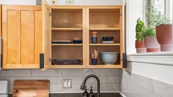 Una cocina con armarios de madera, una encimera, un lavabo con grifo y plantas en macetas en el alféizar.