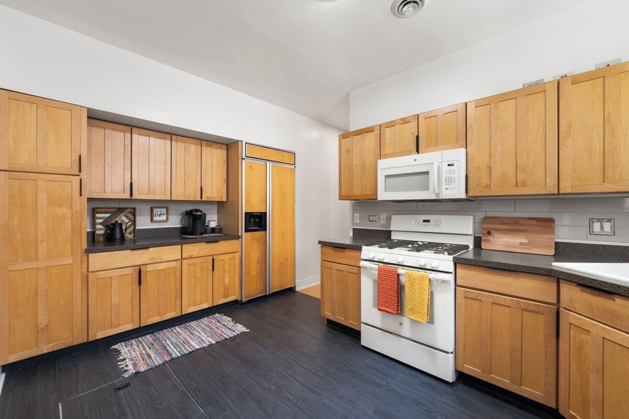 A modern kitchen with wooden cabinets, a microwave, a stove, and a coffee maker.
