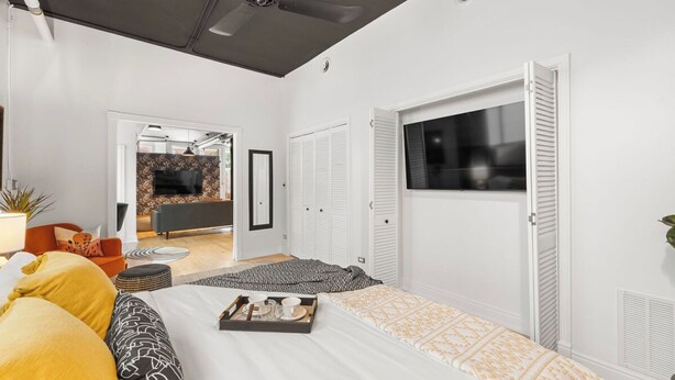 A modern bedroom with a bed, a window, and a view of an outdoor area. - The Lincoln Square Hideaway (Chicago)