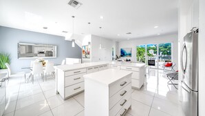 Une cuisine moderne avec des meubles blancs, un îlot central et un coin repas avec des chaises.