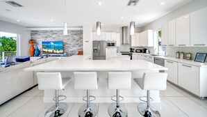 Une cuisine moderne avec des meubles blancs, des appareils en acier inoxydable et un îlot central doté de tabourets de bar.