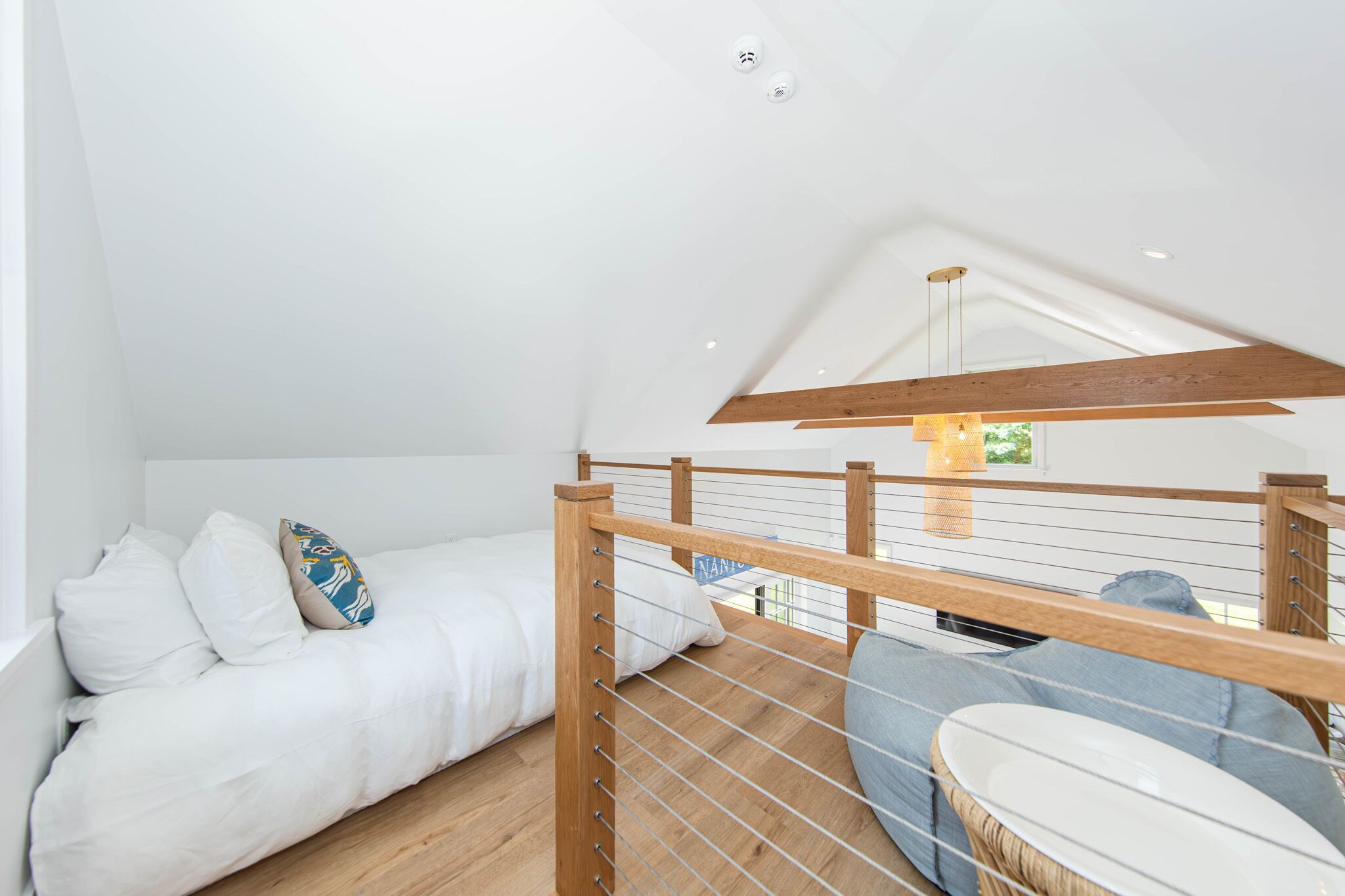 Une chambre avec un lit superposé, une poutre en bois au plafond et un luminaire suspendu.