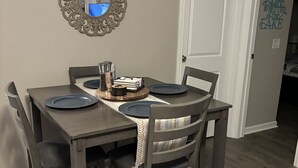A dining table with dark wood chairs, a decorative mirror, and a wall with a sign.