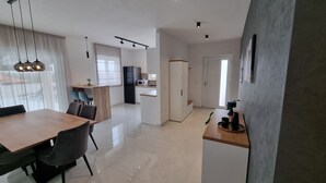 A modern kitchen with a microwave, refrigerator, and a dining area with a table and chairs. - Beautiful newly built villa with private pool in a small village in Istria (Sveti Petar u Šumi)