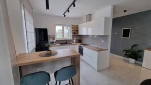 A modern kitchen with white cabinets, a wooden countertop, and two blue chairs. - Beautiful newly built villa with private pool in a small village in Istria (Sveti Petar u Šumi)