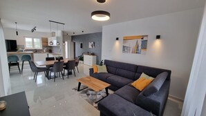 A modern living room with a grey sofa, wooden coffee table, and a dining area with a white table and chairs. - Beautiful newly built villa with private pool in a small village in Istria (Sveti Petar u Šumi)