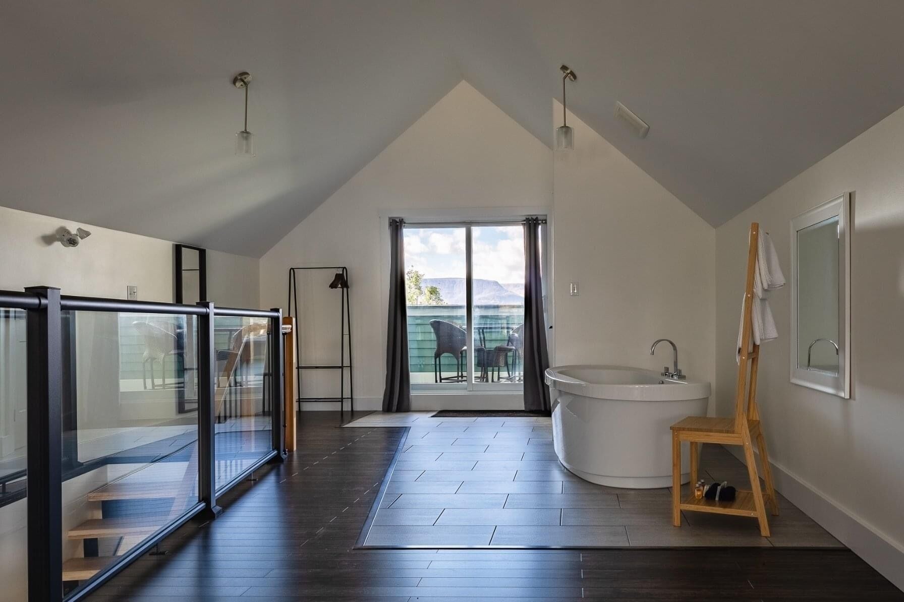 A modern bathroom with a freestanding bathtub, a glass-enclosed shower, and a large sliding glass door leading to a balcony.
