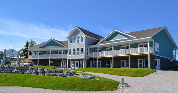 A two-story hotel with a central entrance, multiple balconies, and a well-maintained lawn.