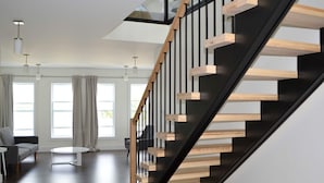 A modern staircase with wooden steps and black railings, leading to a second floor. - The Tides Inn (Norris Point)