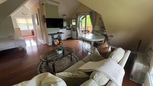 Una stanza mansardata con un letto, un tavolo da pranzo e una TV.