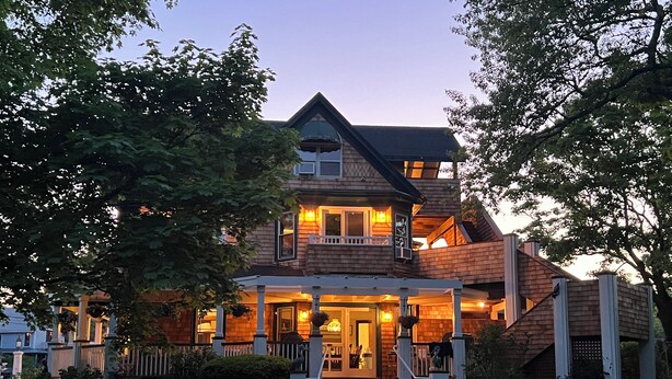 Una casa di legno a due piani con un portico e una scala che conduce all'ingresso.