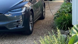 Un'auto parcheggiata su un vialetto sterrato, con una casa sullo sfondo.