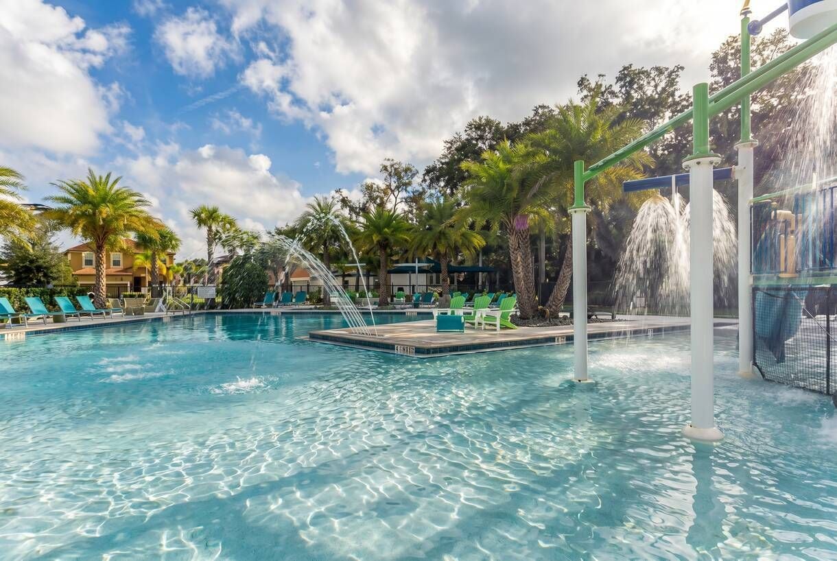 A swimming pool with clear water, surrounded by palm trees and lounge chairs.