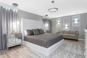 Une chambre moderne avec un grand lit, une table de chevet, un canapé et des luminaires fixés au mur.