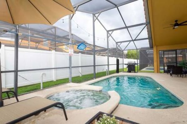 Une piscine intérieure avec un jacuzzi, entourée d’un espace abrité doté d’un toit en verre.