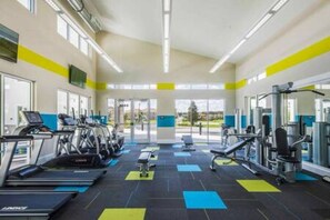 Une salle de sport équipée de tapis de course, d’appareils de musculation et d’un mur recouvert de miroirs.