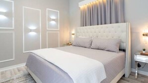 Un dormitorio con una cama grande, una mesita de noche e iluminación en la pared.