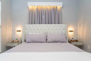 A bedroom with a tufted headboard, two bedside tables with lamps, and a bed with a quilted pillow. - 4BR Pool & Spa Home Near Disney (Kissimmee)