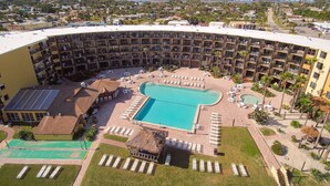Un hotel con una piscina grande, varios balcones y vistas del entorno.