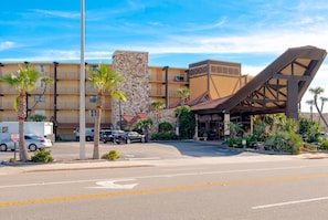 Un hotel con fachada de piedra, varios balcones y una estructura metálica distintiva al frente.