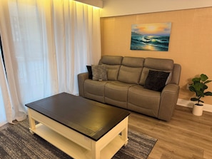 Una sala de estar con un sofá, una mesa de centro, un cuadro y una planta en maceta.
