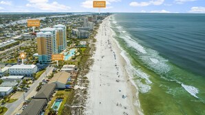 Un paisaje urbano costero con playa, un hotel y un parque.