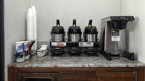 Una estación de café con tres máquinas de café, un dispensador de agua caliente y un dispensador de crema para café.
