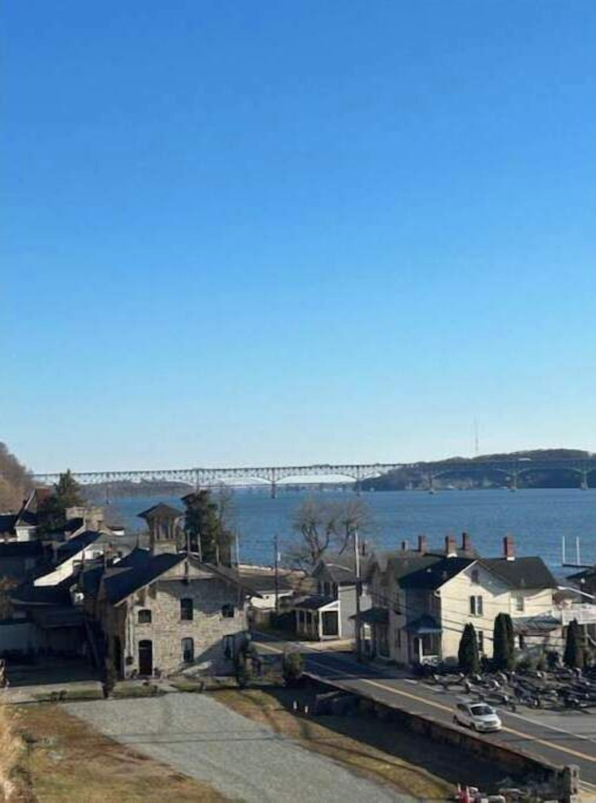 Une ville côtière avec des bâtiments en pierre, un pont en arrière-plan et un ciel bleu dégagé.