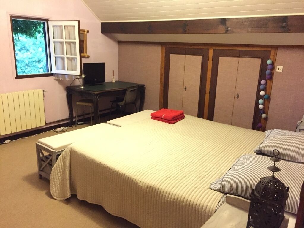Un dormitorio con cama, escritorio, silla, radiador y armario.