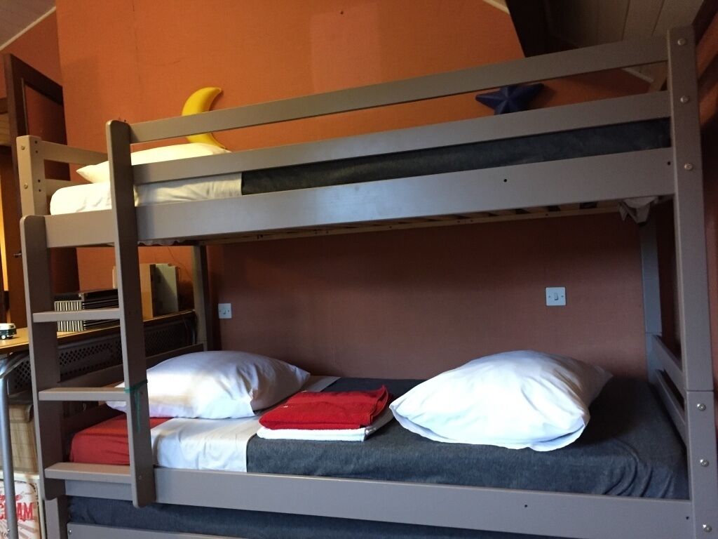 A bunk bed with two levels, each with a pillow and a blanket.