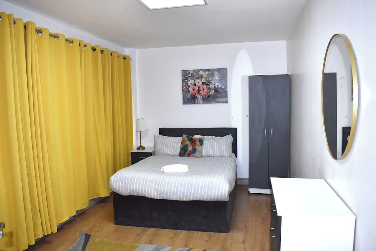 A bedroom with a bed, a nightstand, a dresser, a mirror, and a painting on the wall.