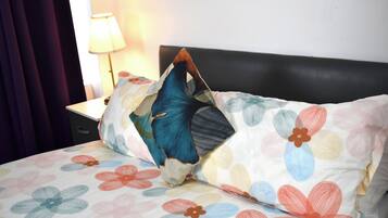 Un lit avec une couvre-lit à motifs floraux et un oreiller aux couleurs bleu et orange.