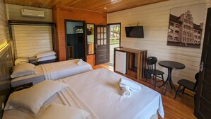 A room with two beds, a small table, a TV, and a door leading outside. - Pousada Scursel (Ibirama)