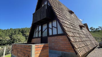 Une maison traditionnelle avec un toit à forte pente, une base en briques et une partie supérieure en bois.