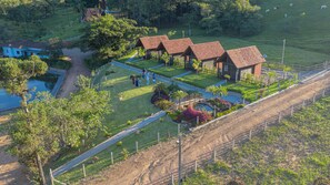 An aerial view of a resort with multiple cabins, a swimming pool, and well-maintained gardens. - Pousada Scursel (Ibirama)