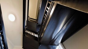 A staircase with black railings and a tiled floor. - Mortdale Hotel (Mortdale)