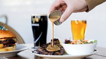 Un plato con carne, una jarra de cerveza y un bol de ensalada.