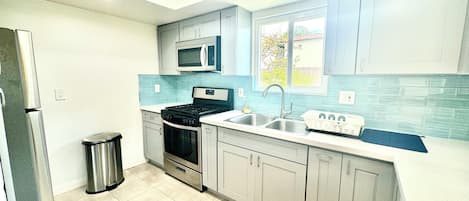 A modern kitchen with a stainless steel refrigerator, a built-in microwave, a double oven, and a sink with a window above it.