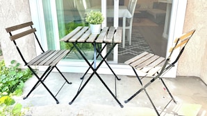 An outdoor patio with a table and two chairs, a potted plant, and a glass door leading to an interior space. - Luxury home near Disney land. Entire place!
 (Orange)