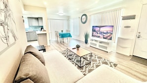 A modern living room with a sofa, a TV, and a dining area with a table and chairs. - Luxury home near Disney land. Entire place!
 (Orange)