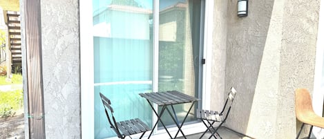 Une terrasse dotée d’une porte-fenêtre coulissante, d’une petite table, de deux chaises et d’un banc en bois.