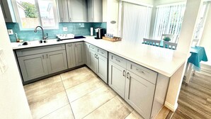A modern kitchen with grey cabinets, a white countertop, and a built-in dishwasher. - Luxury home near Disney land. Entire place!
 (Orange)