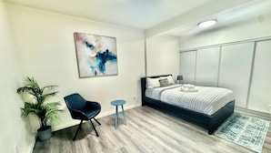 A modern bedroom with a bed, a chair, a small table, a potted plant, and a painting on the wall. - Luxury home near Disney land. Entire place!
 (Orange)