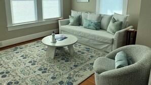 Ein Wohnzimmer mit einem weißen Sofa, einem runden Couchtisch und einem gemusterten Teppich.