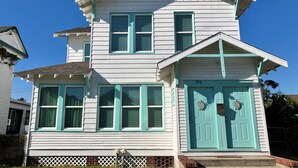 Ein zweistöckiges Haus mit einer hellblauen Tür und Fenstern, der Hausnummer '3312' an der Tür und einer kleinen Veranda mit Stufen.