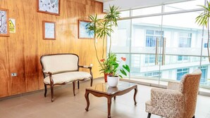 A room with a wooden wall, two upholstered chairs, a glass coffee table, and a potted plant. - Gran Hotel Villa Del Sur (San Vicente de Cañete)