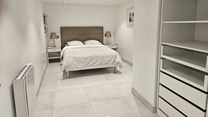 Ein modernes Schlafzimmer mit einem großen Bett, zwei Nachttischen, einem Heizkörper und einer eingebauten Regaleinheit.