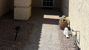 A building entrance with a tiled roof, a large arched doorway, and a small garden area with a bird sculpture and a potted plant. - Enjoy an oasis's over looking the golf course  (Fort Mohave)