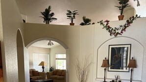 A spacious living area with a large sofa set, a coffee table, and a decorative vase. There is a hallway leading to another room with a door and a potted plant. - Enjoy an oasis's over looking the golf course  (Fort Mohave)